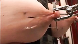 Master sticks pointy sharp needles in her huge suspended tits