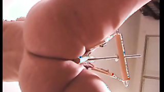 Fetter Mann mit schwarzer Maske drückt ihre Brustwarzen mit Schraubstöcken