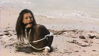 Nylon wearing babe escaped abduction but keeps getting stuck in wet sand