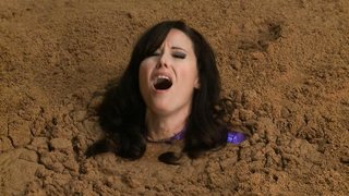 Supergirl mit großen Brüsten im Latexanzug wird lebendig begraben