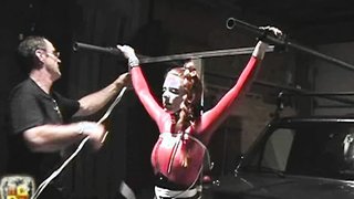 Sexy redhead with amazing hair bound to a truck in pink suit