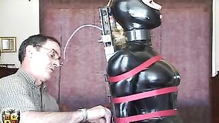 Latex hottie is sitting in the chair of pain that's her master made