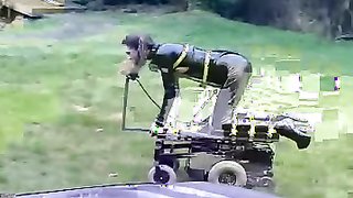 Chica sumisa con traje de látex chupa un consolador en pose de perrito