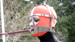 Dominated latex doll in metal mask has a bared pussy