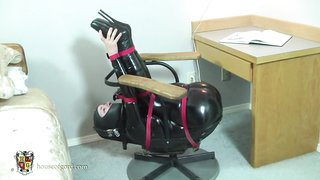 Latex-Babe ist in einer seltsamen Position gefaltet und mit Klebeband fixiert